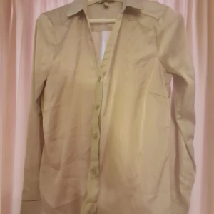 Skjorta från hm - Säljer denna fina satin / siden imitation skjorta från HM. Färgen framkommer inte riktigt på bild men skulle säga att den är grå/ beige   Skriv till mig vid intresse använd ej köp nu funktionen❣