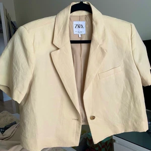Kortärmad blazer fr. ZARA - ✨ANVÄND ENDAST 1 GÅNG✨ Säljer denna superfina kortärmade blazer från Zara. Har en lite gammeldagsvit/beige/gul färg med inslag av linne i materialet, dock inte i så tunn som linne är. Kort i modellen. Jättefint att ha över sommarklänningen ju?! Storlek L men rätt liten i storleken. 