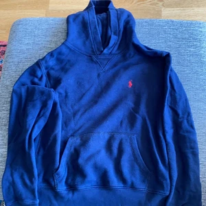 Polo RalphLauren - Mörkblå hoddy med huva och diskret tryck framtill. Genomgående ficka på magen. 