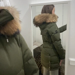 Hollies jacka - Subway grön (stor päls) - Säljer med sorg min snygga jacka från Hollies i grön färg som är en färg vars passar med allt. Stor fin äkta päls från tvättbjörn på kragen. Köpt på butiken Trelupi för 4.499 kr. Den säljs inte längre i äkta päls utan endast fusk❌. Hela jackan är i perfekt skick, precis som ny. Inga skador alls. Den är en varm fodrad dunjacka, släpper inte in kyla, har en innerficka samt två rymliga fickor. Avtagbar päls som också är i perfekt skick. Strl 38 men passar mig som har S då den är mindre i storleken.