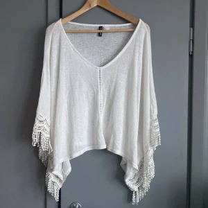 Poncho  - Vit poncho med mönster i Stl s