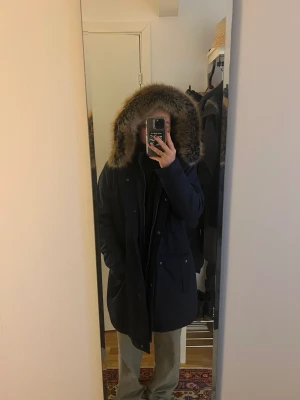 Barbour jacka - Superfin mörkblå vinterjacka från Barbour. Mysig luva med päls. Varm och skön samt vattenavvisande. I nyskick, använd 1 gång. Säljer då den inte längre passar. Strl 44/46 men funkar även för 40/42 om man vill ha en tjockare tröja under. Nypris: 4000kr.