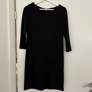 Klänning - En svart klänning från Vila i storlek XS. Mjukt tyg med dragkedja i ryggen och tre kvarts ärmar. Använd 1-2 gånger, mkt fint skick! Sitter inte så tajt utan mer en rak passform.