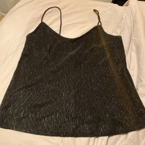 Glittrig svart topp - Säljer en svart topp med glitter/skimmer. Fint skick, upplever att den passar både S & M
