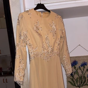Balklänning  - En beige maxiklänning med långa ärmar, använt 1 gång, nyskick. Paljetter på framsidan och baksidan av klänningen. Köpt från London. 