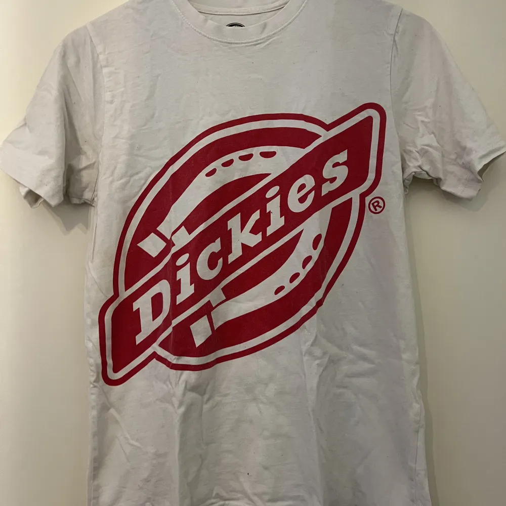 En basic vit t-shirt med rött Dickies märke på framsidan. T-shirts.