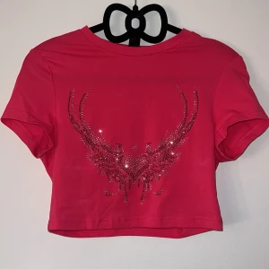 Rosa baby tee - Rosa baby tee med strass/rhinestones. Köpte för 60kr på Shein. Superfin men lite för liten på mig. Den har några ljusare märken (syns på andra bilden) men det kan hända att det går bort i tvätten.