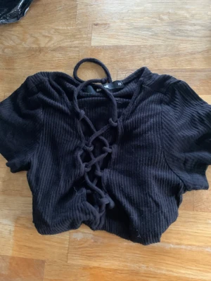 Svart topp - Svart topp/T-shirt från Bikbok, Stl xs. Superfin med knytning/öppning över bysten. Lite croppad men går iallafall till naveln. Superfint skick knappt använd. 