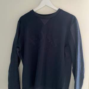 En blå Hugo Boss tröja i storlek Medium. Som nyskick. Väldigt skönt material. Köpt i NK Stockholm.
