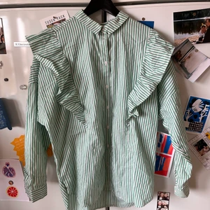 Randig skjorta  - Grönvit-randig skjorta från Monki med volanger.