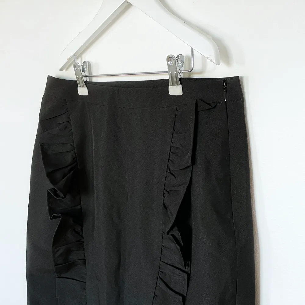 En festlig svart fitted kjol med två volangdetaljer på framsidan. Aldrig använd därmed nyskick, det är storlek M dock skulle jag säga att den är lite små i storleken.   Passar till allt och går att styla upp och ner.. Kjolar.