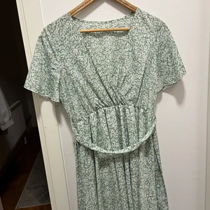 Blommig klänning - Sockersöt grön blommig klänning. Knyts i midjan. 