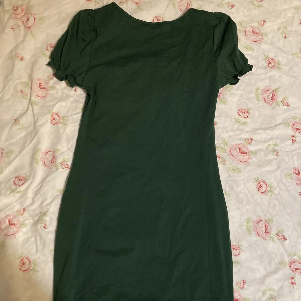 Mörkgrön kort klänning med puffärmar och detaljer runt bysten!. Mekot.