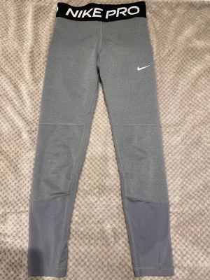 Nike PRO träningstights barn - Tightsen är köpta på Stadium och är använda. Men de är forfarande i ett bra skick, dock finns det en liten defekt på Nike loggan. (Se bild 3) De är i storleken 134/140 och säljs pågrund av att det blivit för små. Köpt för 400 Kr.