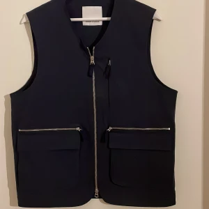 Samsöe Samsöe väst - Samsöe Samsöe väst. Fyra fickor på framsidan, varav två med dragkedja samt en innerficka. Storlek m. Oanvänd.