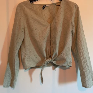En ljus grön blus. - En ljus grön blus med knappar och med knyte. Använd några få gånger men är i bra skick  Storlek:36  