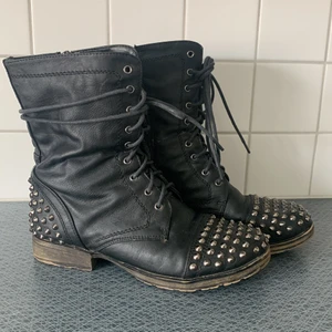 Kängor med nitar  - Storlek 38. Svarta kängor med nitar på tå och häl. Sparsamt använda. Kängorna är lätt fodrade så passar bra till vår/höst och har dragkedja på insidan. 🌸 Frakt ingår ej i pris. 