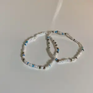 Armband från indiska med elastiskt band. Med vita, blåa och guldiga pärlor. (Kan användas till att ha på ankeln)