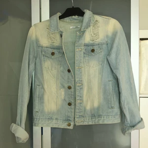 Jeansjacka med slitningar - Ljusblå jeansjacka med slitningar. Medellång. Bra skick då den endast använts ett fåtal gånger. 