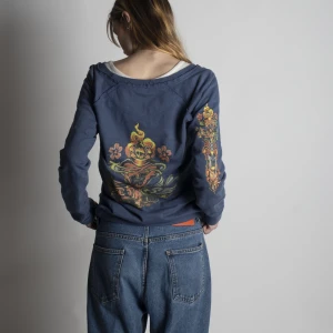 Blå sweater  - Säljer denna blåa pullover med y2k tryck. Personligen tycker jag att den har lite Ed Hardy stil. 