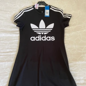 Adidas klänning - Super snygg svart, adidas klänning. Ser ut som en lång T-shirt och kan användas till sommaren eller stranden. Den kommer ner till lite över mina knän och jag är ca 159cm. Den är helt ny också och har storleken 164👗