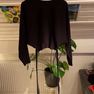 Svart stickadtröja - Svart stickadtröja med snören som man knyter bak.