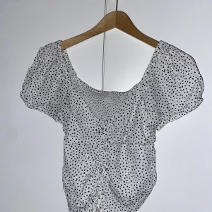 prickig topp  - säljer min jättefin topp den är i bra skick och är knappt använd. den är svart och svit prickig och har liten rosette längst ner på tröjan