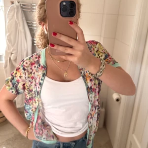 Blommig topp - Söt blommig kortärmad topp med dragkedja💕så fina färger med turkosa kanster, så fin nu till våren💕storlek L men jag har S