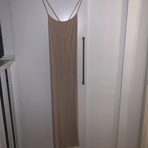 Lång tajt klänning - Lång tajt klänning som har ett kryss i ryggen. Väldigt mjuk och skön. Skims dupe.