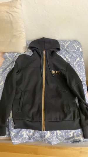 Hugo boss kofta - Säljer en Hugo boss kofta som är slutsåld överallt. I färgen guld och svart. Storelk L. Den passar M bra också. Hör av er bara!