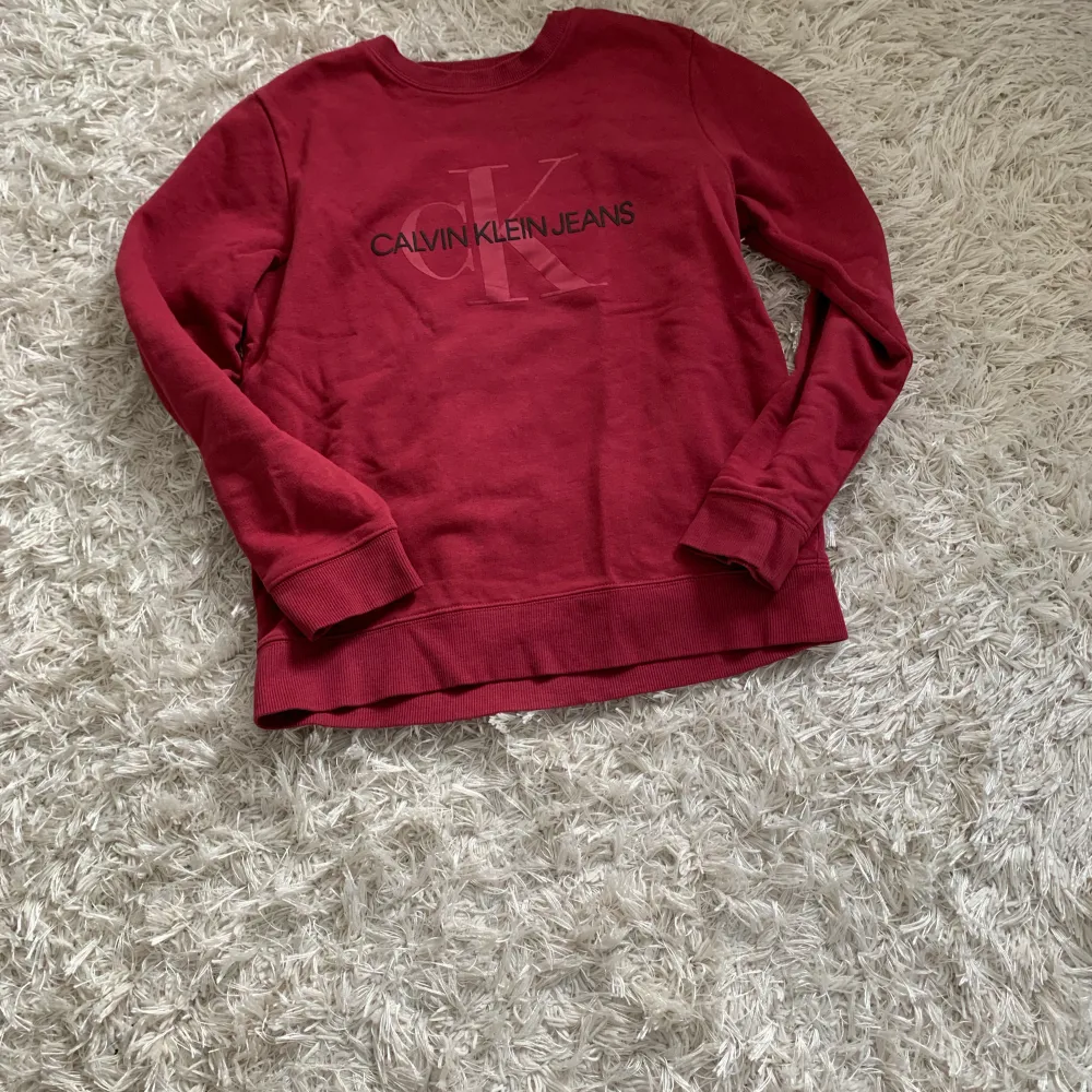 Vinröd långärmad tröjan med märket Calvin Klein köpt från kidsbrandstore! Nästan aldrig använd. Storlek xs och såklart kommer den strykas och tvättas en extra gång innan du köper den!. Hoodies.