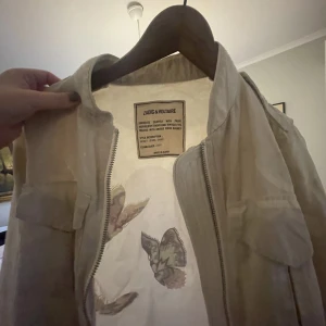 Zadig Voltaire jacka - Ursnygg vår jacka med broderade fjärliar. Jackan har knappt används och köptes i USA för två år sedan. Jackan går inte att få tag på längre, den köptes för 2000kr. Pris kan diskuteras