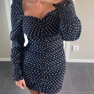 Prickig klänning - Prickig klänning som är uppvikt då den är ungefär knälång. Har en slitning där back men syns ej när man viker upp. 