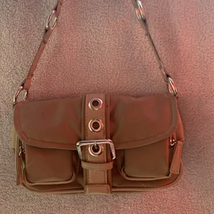 Brun liten Axelremsväska  - Den är brun och fin med mycket fickor som man ja ha saker i 