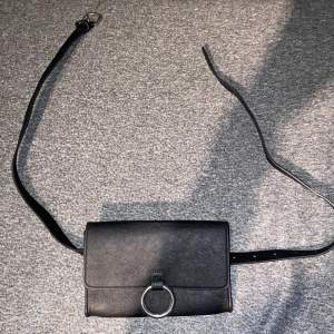 En svart magväska från BikBok med silver detaljer  