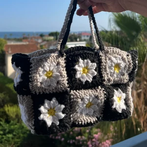 Söt virkad väska med blommor  - Egengjord, virkad väska av mormorsrutor med tusenskönor på. Den är 20 cm lång, 14 cm hög och 6 cm bred. Garnet är 100% bomull. Totalt kostar den 200kr med frakt!