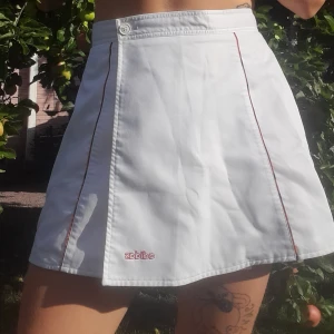 Adidas tenniskjol - Tennisliknande adidas kjol i väldigt fint skick. Den går att öppna upp helt. Man sätter ihop den med liten kardborreband och knapp. Fina detaljer som syns på tredje bilden i rött, lila, orange, gul. Står storlek 38 i men är nog mer 36 och mellan 36-38.