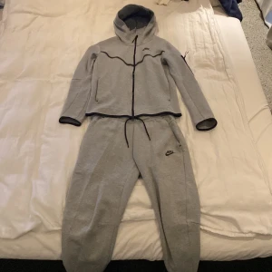 Nike Tech Dress Ljusgrå - Säljer denna i tröja i samband med byxorna  Båda är så gott som nya tröjan använd mer än byxorna, ännu inga hål eller fel på de! S på både tröjan och byxorna