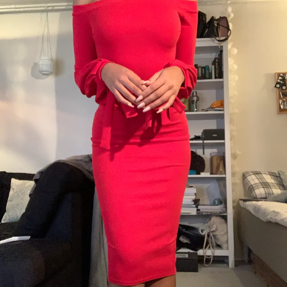 En klar röd bodycon klänning som är off the shoulder och har rosetter på slutet av ärmarna. Enbart använd 2 gånger. Klänningen är från märket BOOHOO och är storlek 36. Fin kvalite och bra för fest eller event.. Klänningar.
