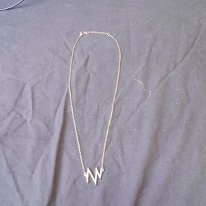 Halsband - Guldigt halsband med smycke som är dekorerat med diamanter. Varken äkta guld eller diamanter