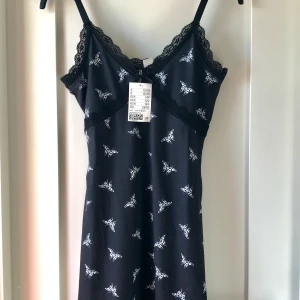 HM Klänning - Klänningen har vita fjärilar på hela fram och baksida. Den har justerbara axelband. Sitter över knäna på mig som är 163 cm lång. Den är aldrig använd, endast provad. Prislapp kvar (se bild) Säljer den därav endast lite billigare. Köpare står för frakt. Kolla gärna in mina andra annonser 🥰