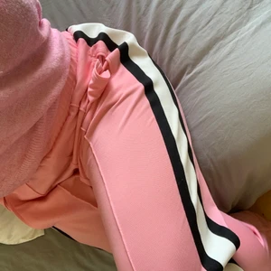 Ganni tracksuit pants - Byxorna till ett rosa Ganni-set! Tröjan sälja separat på min profil 💕 avslappnad passform, jag brukar använda dem som mer lågmidjade byxor än de två sista bilderna visar ☺️ Inköpta på NK för några säsonger sedan, väldigt fint skick utan något att anmärka på. Är strl 40, sitter lite oversize på mig som är 36-38 🥰 Frakt tillkommer för köparen, samfraktar vid flera köp!