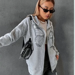 Super skön grå kofta - Super skön kofta som går lite längre ner än vanlig tröja! Grå med glitter i form av en fjäril framtill! Använd 1 ggr! Känns som en medium men på lappen står det Large