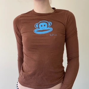 långärmad t shirt från Paul frank  - Brun långärmad t shirt från Paul Frank med blå patch på bröstet. Fint vintage skick, inga uppenbara defekter. Märkt som en storlek small och sitter true to size på mig som brukar ha storlek small/36 i toppar. Mått från armhåla till armhåla 39 cm, från axel till nedre sömnad 54 cm. Kan mötas upp på södra sidan av stockholm annars står köparen för frakt 66kr. Skriv vid frågor 💌