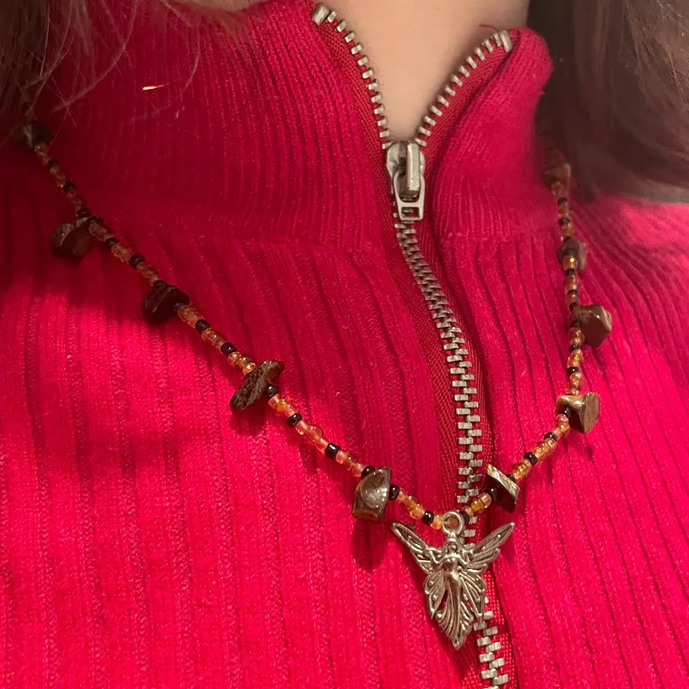 Halsband med silvrig kedja, kristallen tigeröga, diverse glaspärlor och en älva av rostfritt stål🧚♀️. Asusteet.