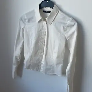 vit skjorta i en mer åtsittande modell med ärmar som går att vika upp snyggt! säljes för att den inte kommer till användning 
