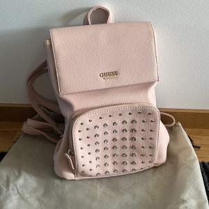 Rosa Guess ryggsäck, lite sliten baktill men går att använda om man ej har tunga saker i den. 30cm hög, 28cm bred och 12 cm djup.