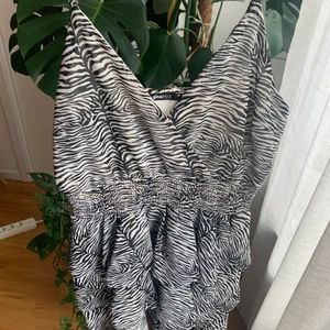 Klänning från gina tricot strl 40 - Sjukt söt klänning i zebra mönster från Gina Tricot. Har volanger på kjolen. Storlek 40, använd 1-2 gånger. Resår i midjan och axelbanden går att justera! 