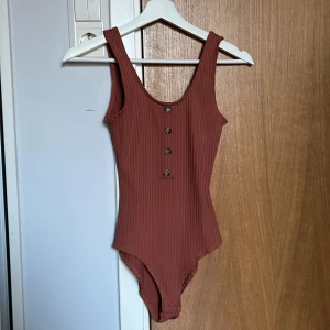 Body  - En ribbad body från HM i storlek XS. Knapparna är endast detalj. Kan även skicka om önskas, fraktalternativ kan diskuteras.