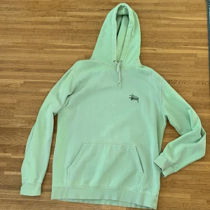 Stussy hoodie - En nice stüssy hoodie i blekt grön färg. Stussy logga på ryggen. Hål under armhålan som inte syns vid användning. Storlek L
